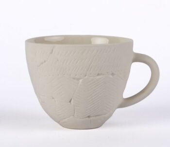 Keraamikud: Kadi Hektor, Janno Roos. Materjal: Portselan. Tassi kõrgus: 8,6 cm ja läbimõõt: 10 cm. Eesti Ajaloomuuseumi tassi eeskujuks on Harjumaalt kiviaegsest Jägalaasulakohalt leitud savinõukillud 330. aastast eKr. Selle ornament on tüüpiline kammkeraamikale - lohud vaheldumisi kammijäljendiga. Tervena säilinud kiviaegsete savinõude leidmine on üliharuldane, sestap on ka tass justkui kildudest kokku pandud.